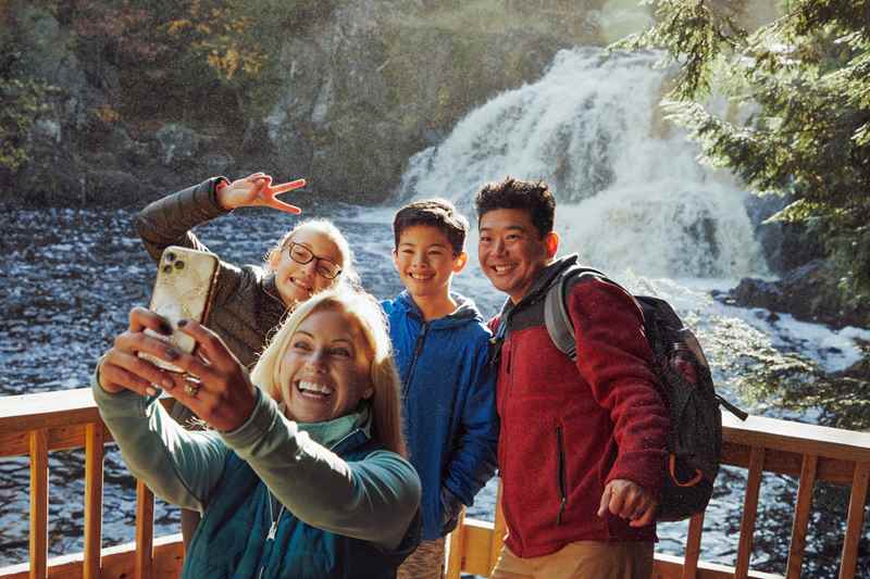 family taking selfie in front of waterfall